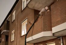 Auto tegen lantaarnpaal tegen balkon